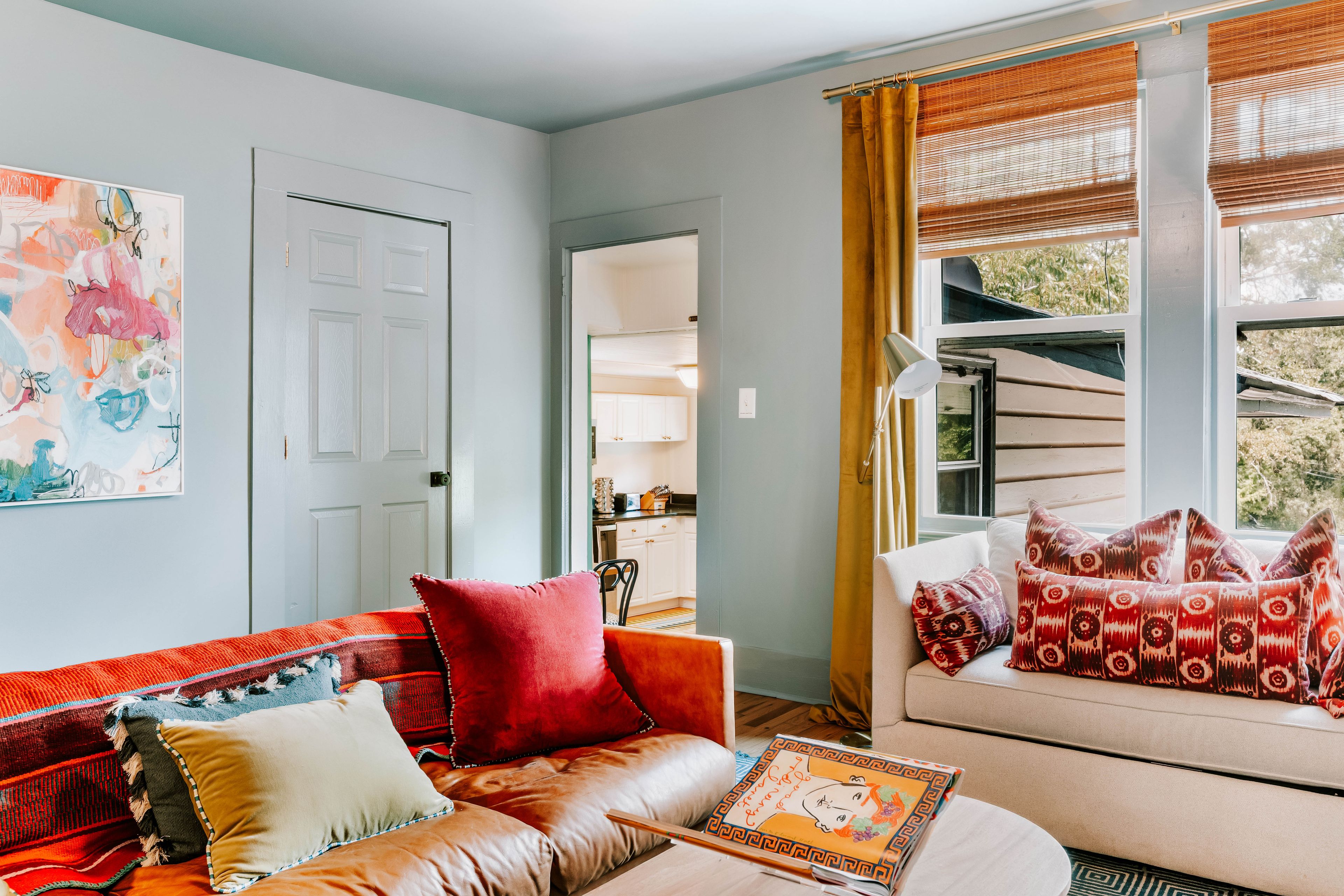 A living room with a sofa, a coffee table, and a window with curtains.