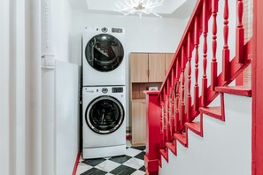 Zona de lavandería con lavadoras apiladas y una escalera roja.