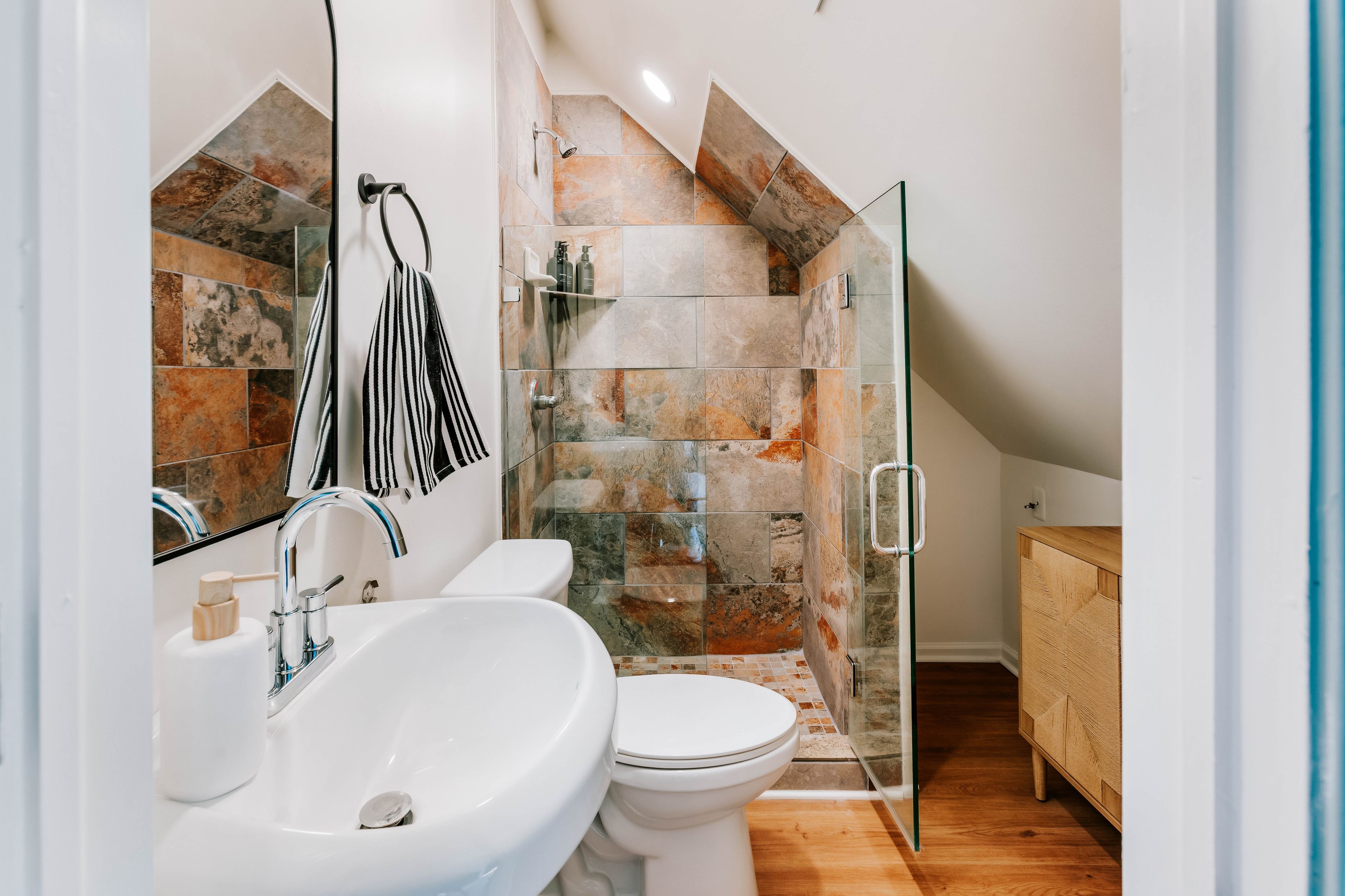 Un baño moderno con un lavamanos blanco, inodoro y zona de ducha con mampara de vidrio.