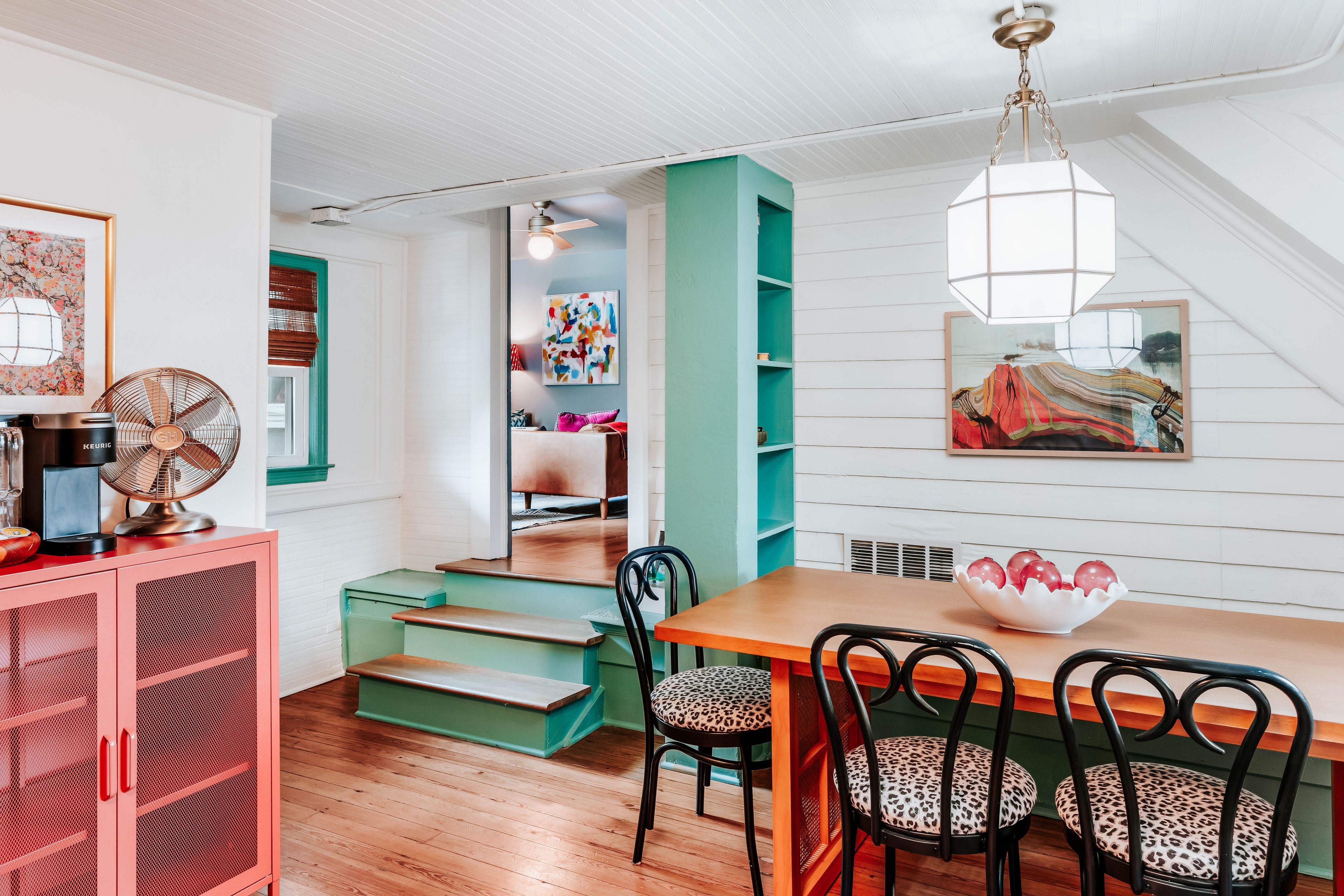 A dining area with a wooden table, chairs, and a ceiling fan.