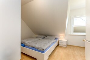 Une chambre à coucher avec un lit, une table de chevet, une fenêtre et un radiateur.