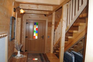 Eine Holztreppe führt zu einem Raum mit einer farbenfrohen Glasfenstertür.