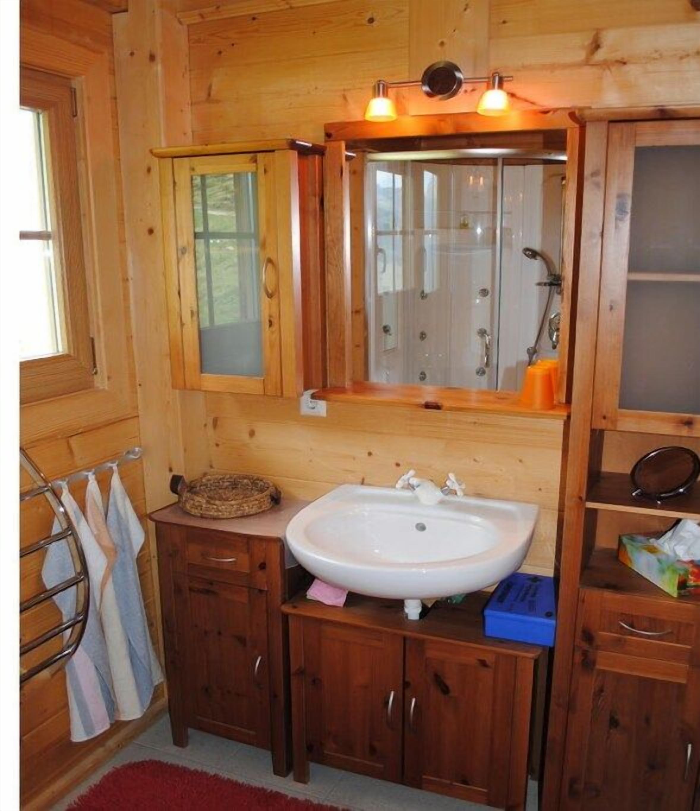 Een houten badkamer met een wastafel, spiegel en kastjes.