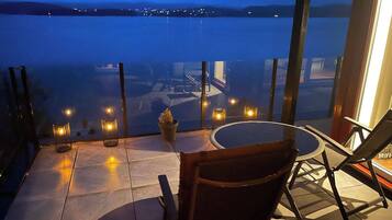 Terraço com vista para a água, mesa redonda e várias cadeiras.