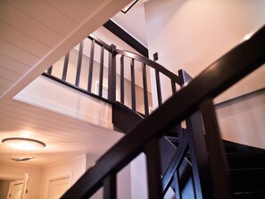 A wooden staircase with a handrail leading to an upper floor.