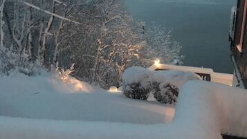 A snow-covered balcony with a view of a lake and trees.