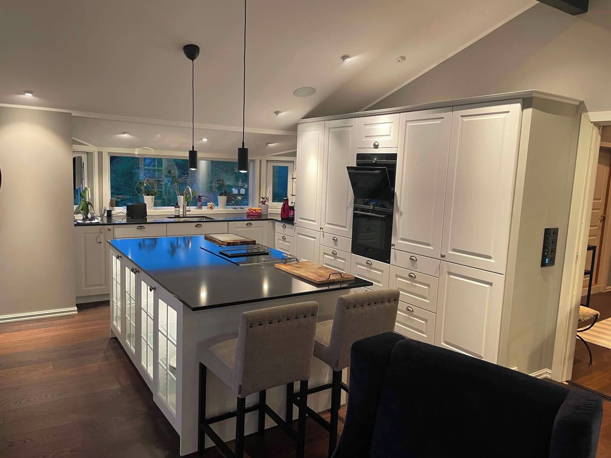 Una cocina moderna con una isla central, armarios blancos y un refrigerador negro.