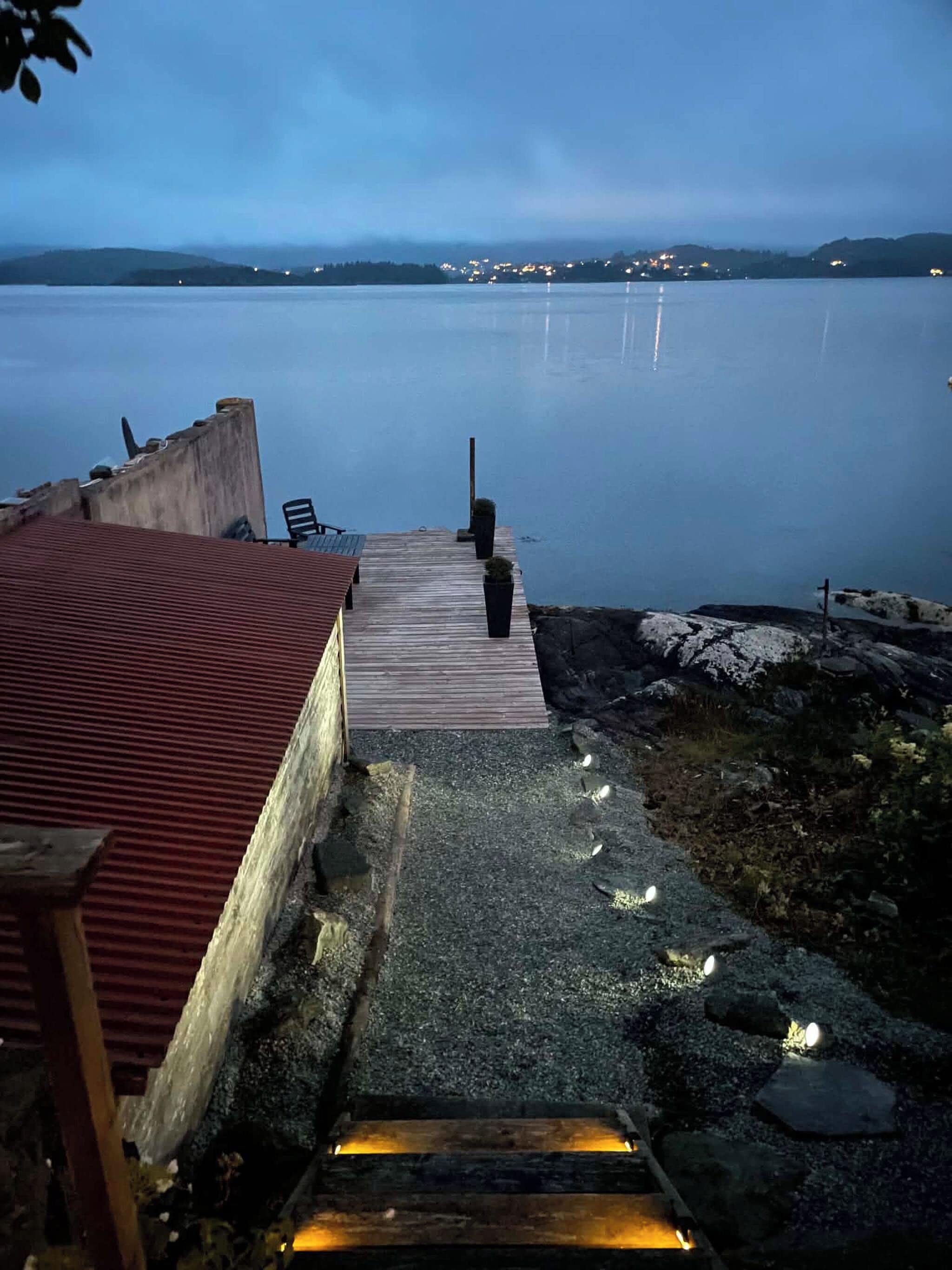 A wooden dock leading to a calm body of water with a distant shoreline.