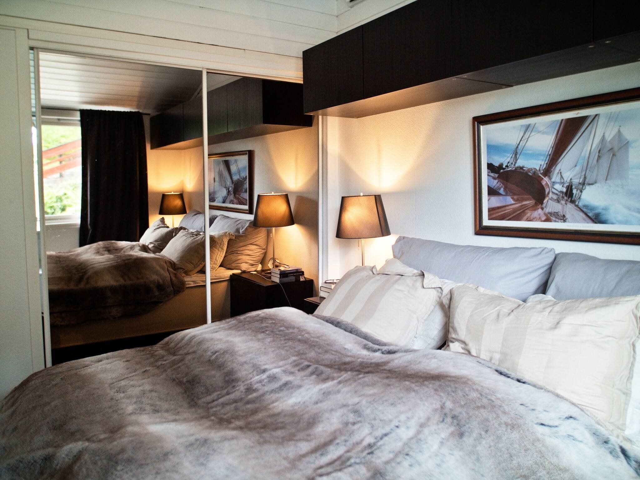 Quarto de hotel com uma cama grande, duas luminárias de cabeceira, um espelho e um quadro na parede.