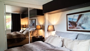 Quarto de hotel com uma cama grande, duas luminárias de cabeceira, um espelho e um quadro na parede.