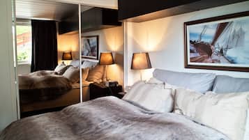 Quarto de hotel com uma cama grande, duas luminárias de cabeceira, um espelho e um quadro na parede.