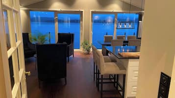 A modern interior with a dining area, seating, and a view of the water.