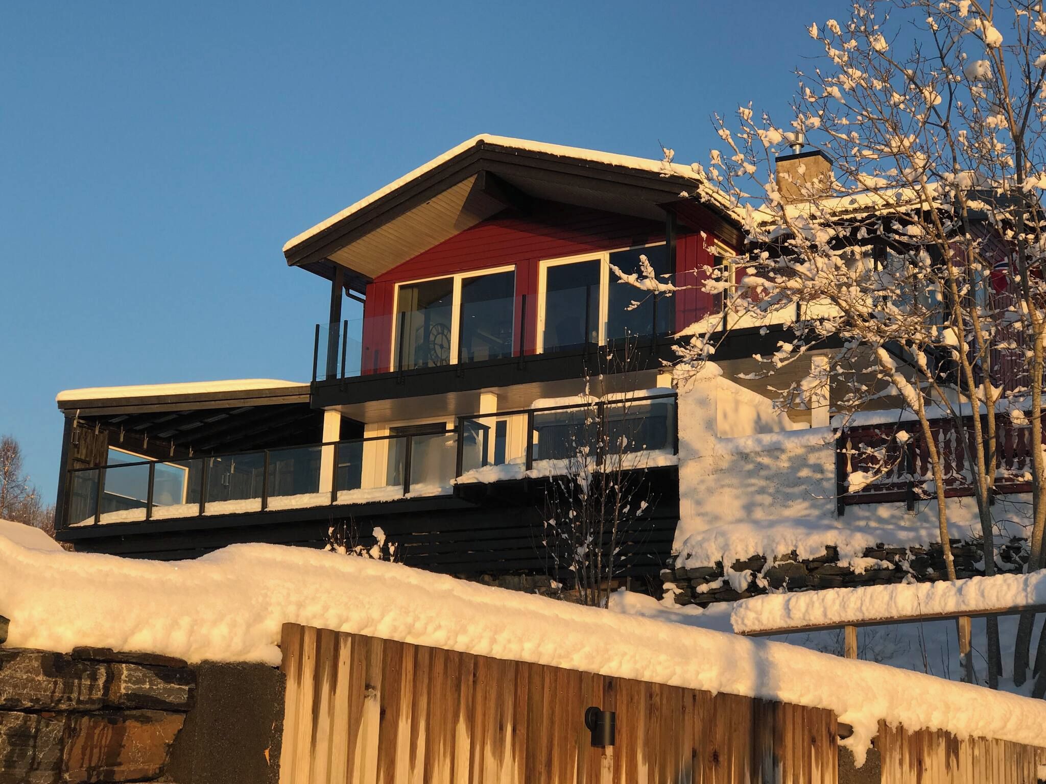 A two-story house with a balcony, surrounded by snow.