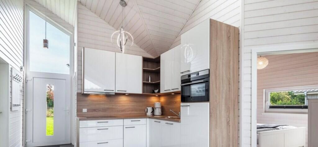 A modern kitchen with white cabinets, a wooden countertop, and a black oven.