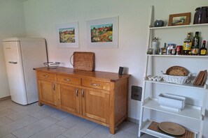 A kitchen with a white refrigerator, wooden cabinets, and a white shelf unit with various kitchen items. - Holiday home with 3 bedrooms (Wiek OT Woldenitz)