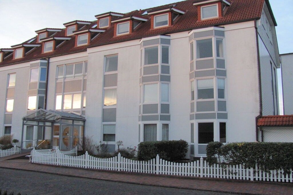 Een meerhoog gebouw met een symmetrische gevel, grote ramen en een witte picket hek.