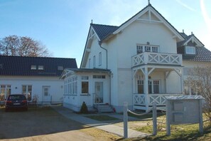 A two-story house with a balcony, a car parked in front, and a utility box. - Stemsperle upper floor (Prerow)