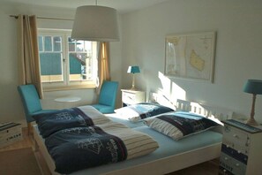 A bedroom with two beds, a window with curtains, a map on the wall, and a small table. - Stemsperle upper floor (Prerow)