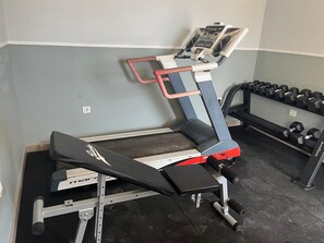 A gym with a treadmill, bench press, and dumbbells. - Apartment 'Sea Breeze I La Manga' with Sea View, Wi-Fi and Air Conditioning (La Manga del Mar Menor)