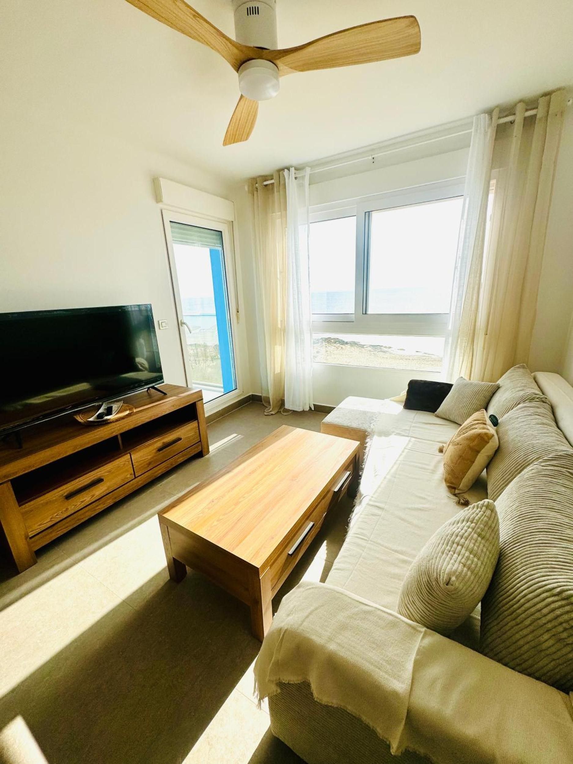 Un salon équipé d’un téléviseur, d’un meuble de rangement en bois, d’un canapé et d’un ventilateur de plafond.