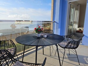 A round table with chairs on a balcony overlooking a body of water. - Apartment 'Sea Breeze I La Manga' with Sea View, Wi-Fi and Air Conditioning (La Manga del Mar Menor)