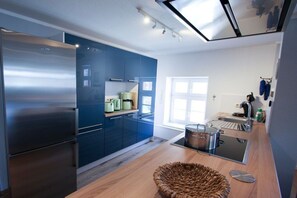 A modern kitchen with a built-in oven, a stainless steel refrigerator, and a large window providing natural light. - Holiday apartment in Barth with swimming pool (Barth)