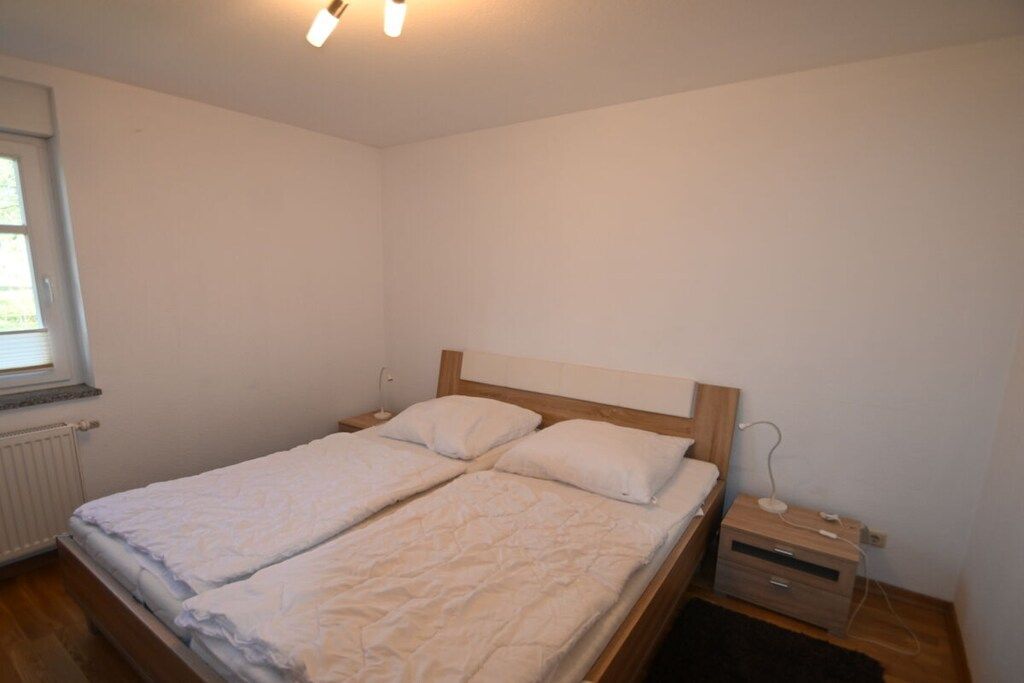 Ein Schlafzimmer mit einem Doppelbett, einem Nachttisch und einem Fenster.