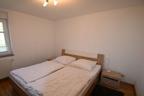 Une chambre à coucher avec un lit double, une table de chevet et une fenêtre.