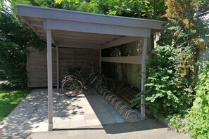 A covered bike storage area with a wooden fence and a concrete pathway. - LEE in the Captain's House Ostseerose (Travemünde)