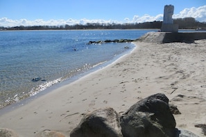 A beach with clear water, a stone monument, and a distant shoreline. - LEE in the Captain's House Ostseerose (Travemünde)