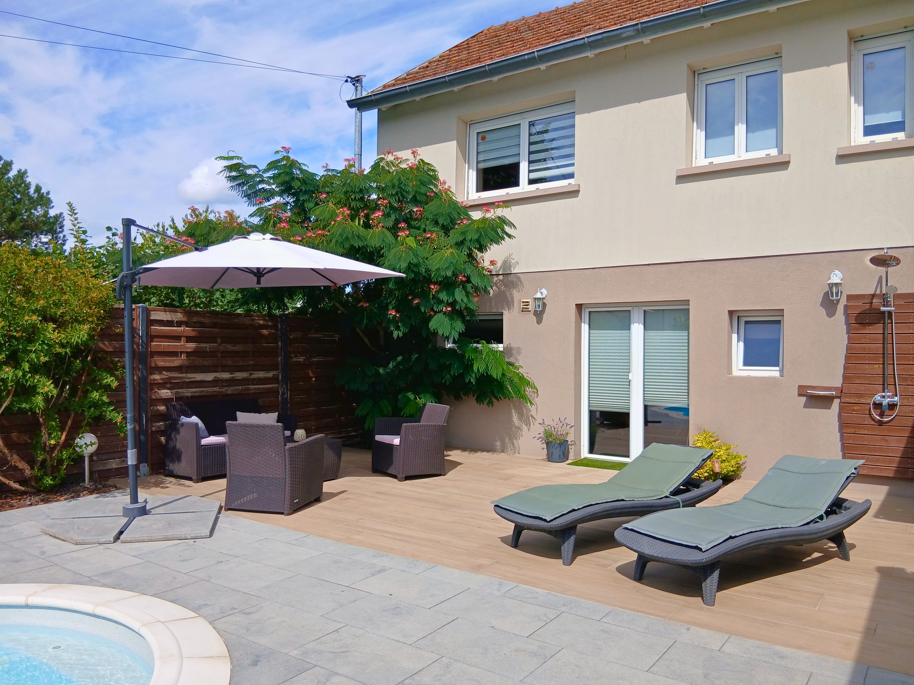 Un patio trasero con un jacuzzi, mobiliario exterior y una zona de estar techada.