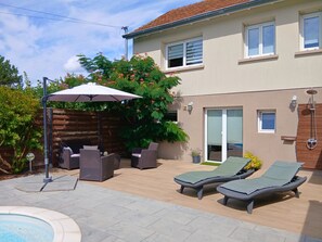 Ein Garten mit Whirlpool, Gartenmöbeln und einer überdachten Sitzgelegenheit.