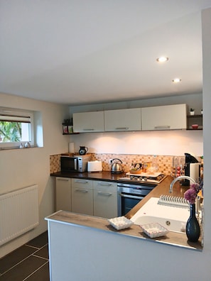 A modern kitchen with white cabinets, a microwave, toaster, kettle, and a sink. - A little haven of peace in Alsace with a pool (Mertzwiller)
