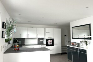 A modern kitchen with white cabinets, a black refrigerator, and a countertop with fruits. - Holiday apartment in Baabe with swimming pool (Baabe)