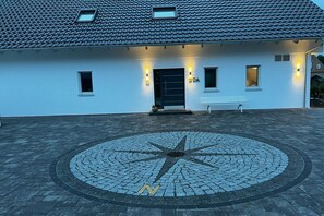 A building with a tiled roof, a compass-like pavement design, and a bench outside. - Holiday apartment in Baabe with swimming pool (Baabe)