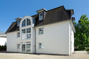 A two-story building with a white facade, multiple windows, and a sloped roof. - 4 (Coastal Rest) in Villa Vesta (Ostseebad Binz)