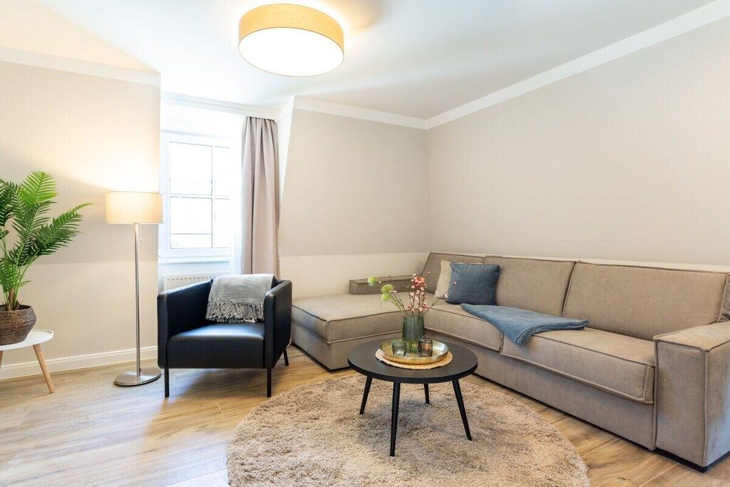 Una sala de estar moderna con un sofá, una mesa de centro, una lámpara de pie y una planta en maceta.