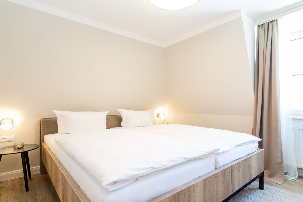 Hotellihuone, jossa on suuri sänky, yöpöydät ja ikkuna, jossa on verhot.