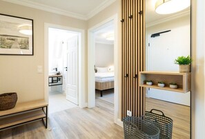 Ein Flur mit einer Bank, einer Wand aus Holzleisten, einem Regal mit Pflanzen und einem Korb.