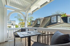 A balcony with a table and chairs, a white railing, and a view of neighboring houses. - 6 (Starfish) in Villa Vesta (Ostseebad Binz)