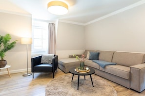 A modern living room with a sofa, a coffee table, a floor lamp, and a potted plant. - 6 (Starfish) in Villa Vesta (Ostseebad Binz)