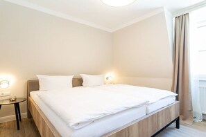 A hotel room with a large bed, bedside tables, and a window with curtains. - 6 (Starfish) in Villa Vesta (Ostseebad Binz)