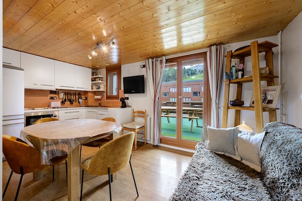 Cocina moderna con armarios blancos, una mesa de comedor con sillas y un amplio ventanal con vistas a un patio.