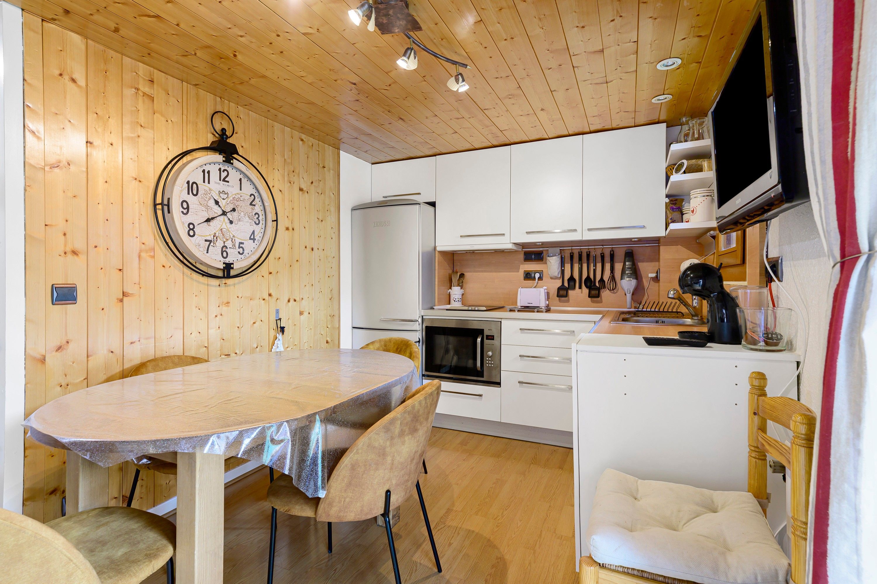 Une cuisine aux murs en bois, avec une table ronde et des appareils électroménagers modernes.