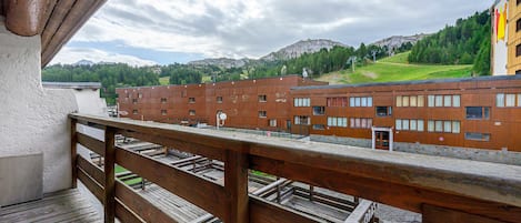A wooden balcony overlooking a row of brick buildings with a mountain in the background.