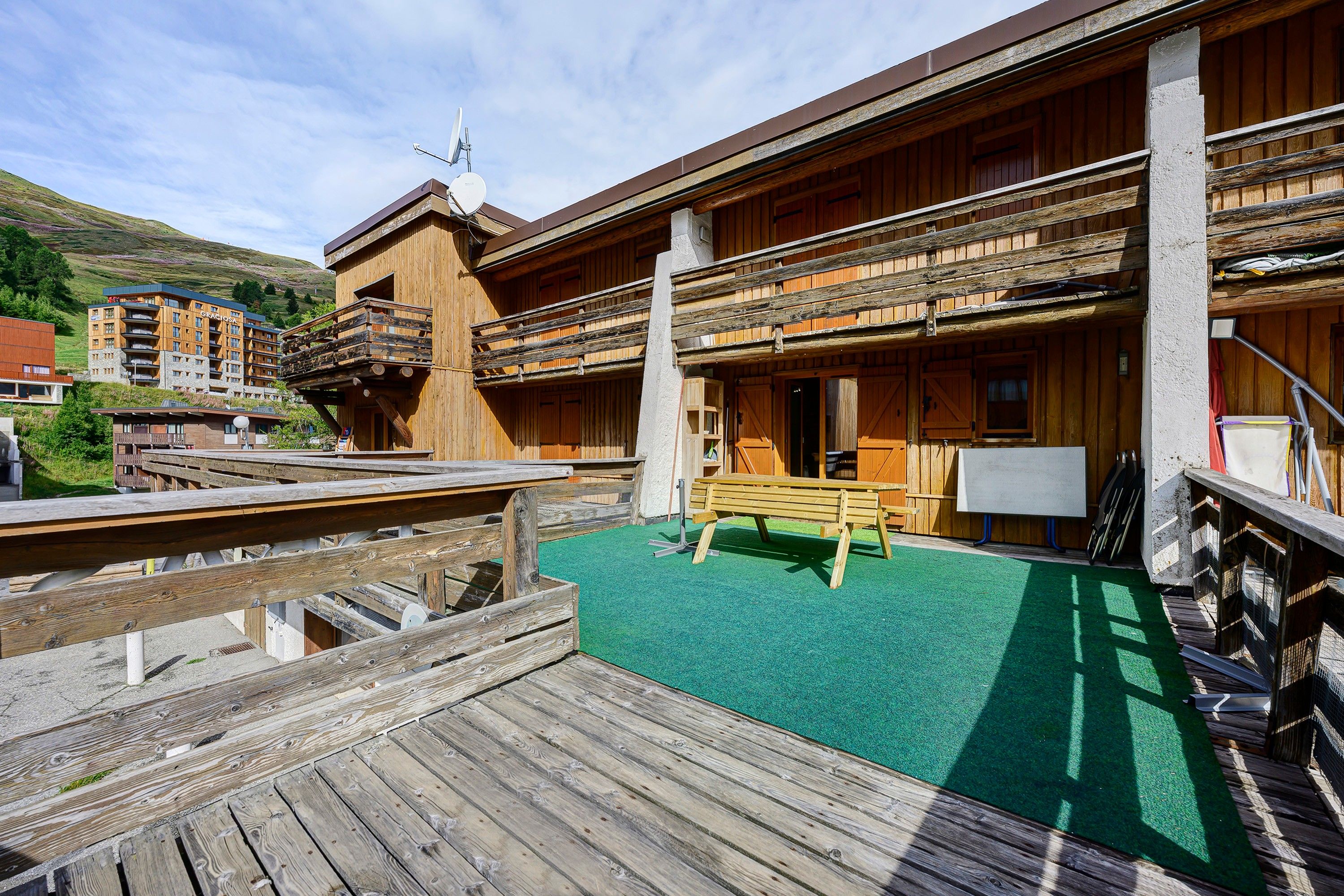 Un bâtiment en bois doté d’un balcon et d’une terrasse en bois avec un banc.