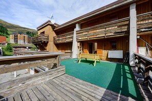 Un edificio de madera con balcón y terraza de madera con un banco.