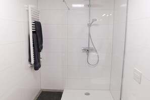 Eine Dusche mit Duschbrause und Handtuchhalter mit Handtuch.