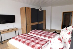 Een slaapkamer met een bed, een bureau, een televisie en een kledingkast.