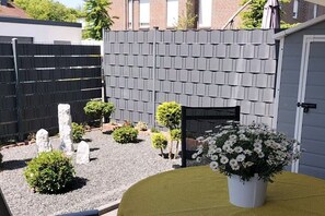 Ein Garten mit Kiesweg, Holzlattenzaun und einem Blumentopf mit weißen Blüten.